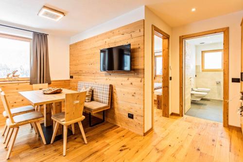 a dining room with a table and a television on a wall at Apartments Milanhof in Ortisei