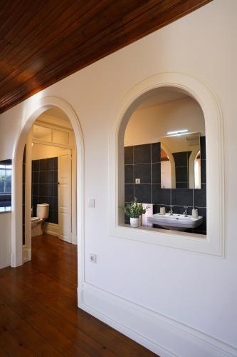 a bathroom with two arched windows and a mirror at Casa da Costeira in Guimarães