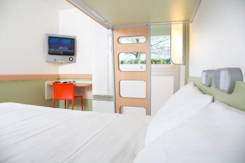 a bedroom with a bed and a table and a tv at ibis budget Caen Mondeville in Mondeville