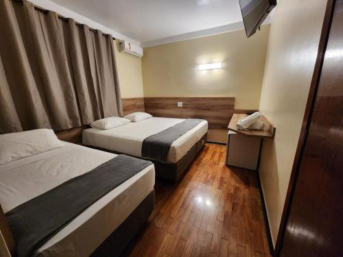 a hotel room with two beds and a television at Aurora Hotel in Ribeirão Preto