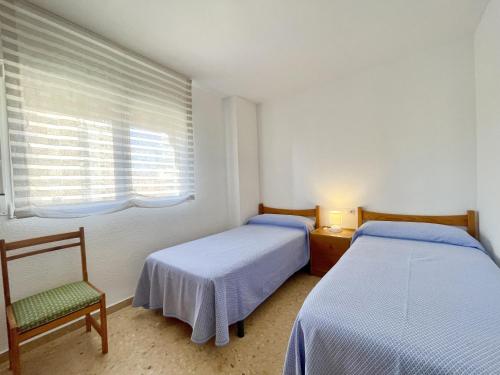 a bedroom with two beds and a chair and a window at Principado Wifi, Airco, Beach and Garden in Benidorm