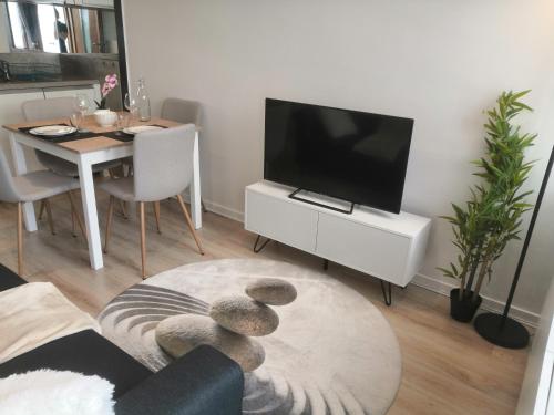 a living room with a television and a table with a dining room at Zenitude - Casa Vostra - Thonon Centre et Thermes in Thonon-les-Bains