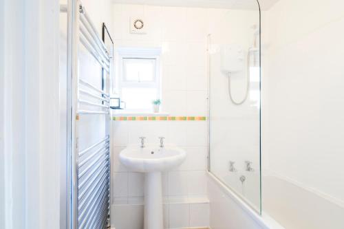 a white bathroom with a sink and a shower at West Lodge- Cosy home from home with 3 bedrooms in Worthing