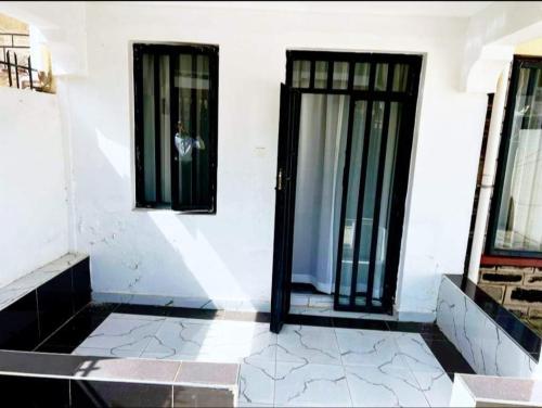 eine offene Tür in einem weißen Gebäude mit Fenstern in der Unterkunft Peaceful Palace in Kisumu