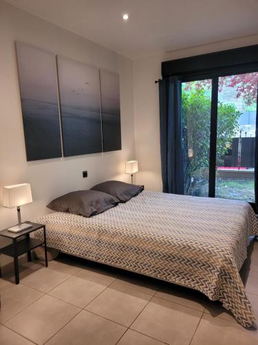 um quarto com uma cama e uma grande janela em APPARTEMENT standing 2 pieces avec jardin entre Paris & Dysney em Bry-sur-Marne