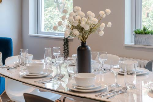 a table with glasses and a vase with flowers on it at Stunning 3 Bed Duplex Apartment in the heart of West Hampstead in London