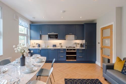 a kitchen with blue cabinets and a table with chairs at Stunning 3 Bed Duplex Apartment in the heart of West Hampstead in London