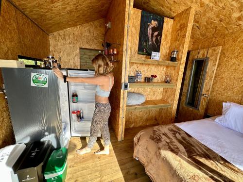 a woman is reaching into a refrigerator in a room at Caralsol Glamping in Rionegro