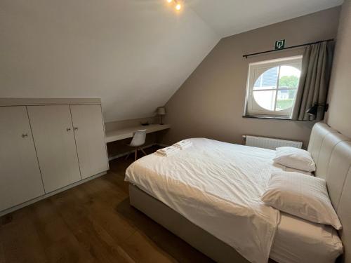 a bedroom with a white bed and a window at Bolderhuys in Bolderberg