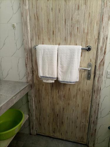 baño con 2 toallas colgadas en una puerta de madera en Sophia house, en Malindi