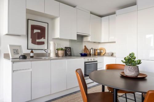 利物浦的住宿－Premium Apartments at Copper House in Liverpool City Centre，厨房配有白色橱柜和桌椅