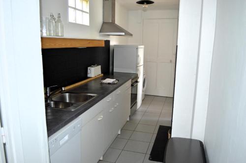 a kitchen with a sink and a refrigerator at La maison de la plage, à 350m de la mer, jardin in Asnelles