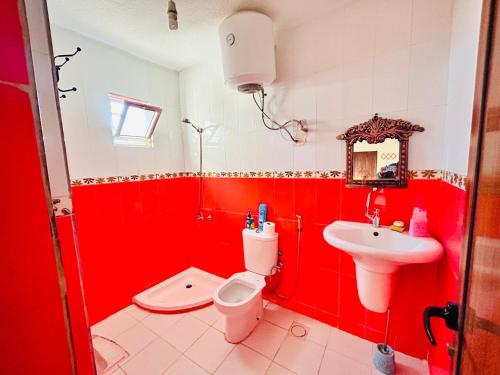 La salle de bains rouge est pourvue de toilettes et d'un lavabo. dans l'établissement apartment between ajloun castle and Jerash ruins, à Jerash
