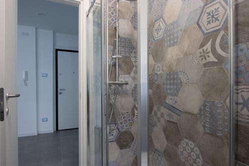 una doccia con porta in vetro e parete a mosaico di [Fibra SuperFast] Politeama Rossetti Modern Suite a Trieste