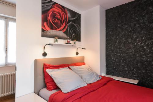 a bedroom with a red bed and a painting on the wall at Au Nom de la Rose - Casa Vostra - Annemasse in Annemasse