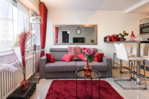 uma sala de estar com um sofá cinzento e almofadas vermelhas em Au Nom de la Rose - Casa Vostra - Annemasse em Annemasse
