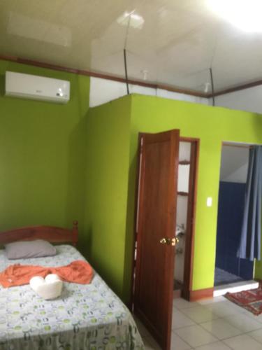 a bedroom with green walls and a bed and a door at Hotel Restaurante Los Cocos in Santa Cruz