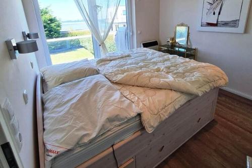 uma cama grande num quarto com uma janela em Holiday home by the sea in Westerbergen on Fehmarn em Albertsdorf