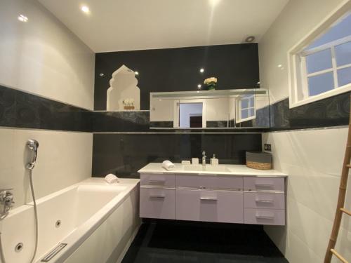 La salle de bains est pourvue d'une baignoire blanche, d'un lavabo et d'une baignoire. dans l'établissement Les Logettes-plage-centre, à Menton