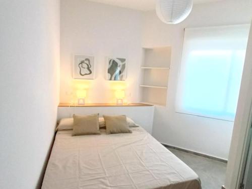 Cama en habitación blanca con ventana en Apartamentos Rincón de Vinatea, en Castellón de la Plana