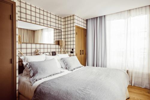 a bedroom with a large white bed and a mirror at Grand Hotel Soleil d'Or in Megève
