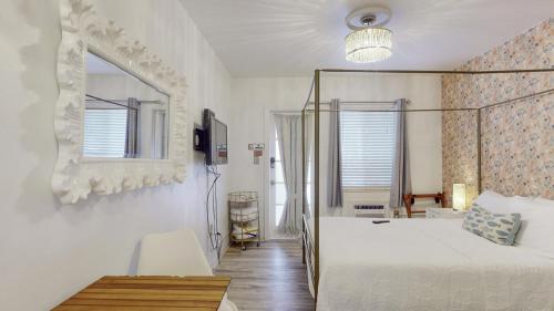 een witte slaapkamer met een bed en een spiegel bij Exclusive Access to a Gorgeous Private Beach 1BR in St Pete Beach