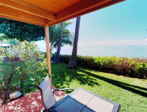 a chair under a porch with a view of the ocean at Hotel Moloka'i in Kaunakakai
