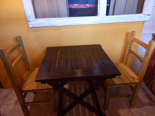 una mesa de madera y 2 sillas junto a una ventana en Cabañas Los Nonos en El Bolsón