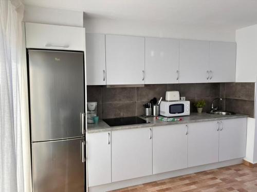 una cucina con mobili bianchi e un frigorifero in acciaio inossidabile di Apartamento Marae a Corralejo