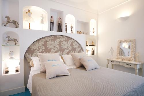 een witte slaapkamer met een groot bed met witte kussens bij fior di lino in Positano