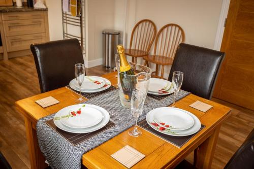a dining room table with a bottle of wine and glasses at Swallow View, A Spacious Base with stunning views in Matlock