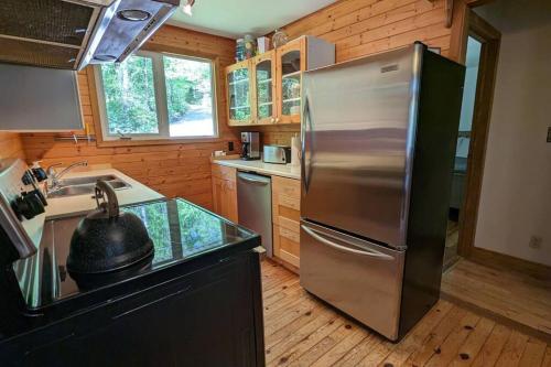 cocina con nevera de acero inoxidable y fregadero en Cozy Cabin on Trout Lake, en North Bay