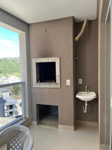 a bathroom with a sink and a tv on the wall at Apartamento à 380m do Mar in Itapema