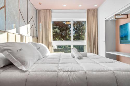 een groot wit bed in een kamer met een raam bij Apartamento Bellagio 2 Suítes e Piscina by Achei in Canela