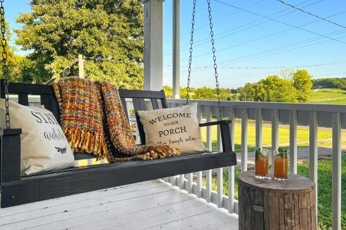 a porch swing with a blanket and pillows on it at Shelbyville Farmhouse with Hot Tub, Fire Pit and Grill in Shelbyville