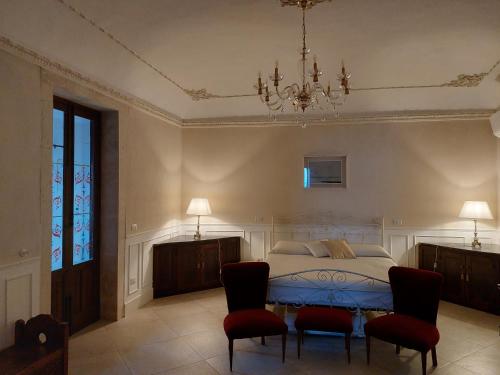 Un dormitorio con una cama con sillas rojas y una lámpara de araña. en Camilla suite, en Siracusa