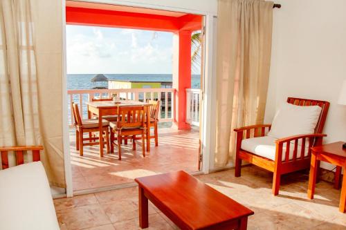 ein Wohnzimmer mit einem Tisch, Stühlen und Meerblick in der Unterkunft Mayan Princess Hotel in San Pedro