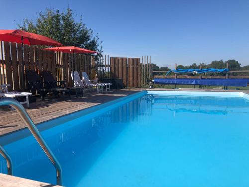 a swimming pool with chairs and umbrellas on a deck at Les Gîtes de La Croix Liaud in Saint-Sulpice-en-Pareds