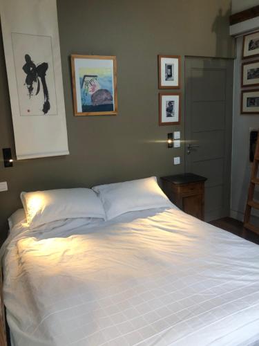 - une chambre avec un grand lit blanc éclairé dans l'établissement Charming apartment on top floor in Marais -5P, à Paris