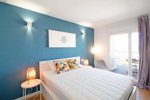 1 dormitorio con 1 cama grande y pared azul en Global Properties, Moderno apartamento con piscina en la playa de Canet, en Canet de Berenguer