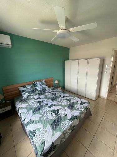 a bedroom with a bed with a green wall at Les Tuileries in Les Trois-Îlets
