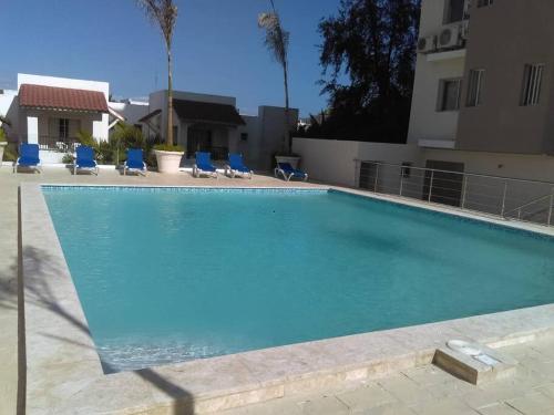 a large swimming pool with blue chairs and a building at Boca del mar, apartamento 207/206 in Cuevas