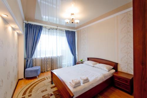 a bedroom with a bed and a window with blue curtains at Five Stars Comfort in Chelyabinsk