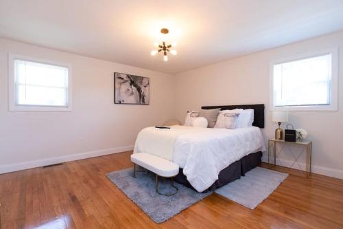 a white bedroom with a bed and two windows at The Charles-South Shore in Randolph