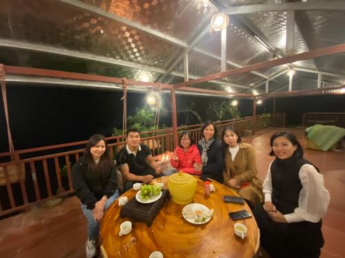 un gruppo di persone seduti intorno a un tavolo di legno di Lanh Sapa Homestay a Sa Pa