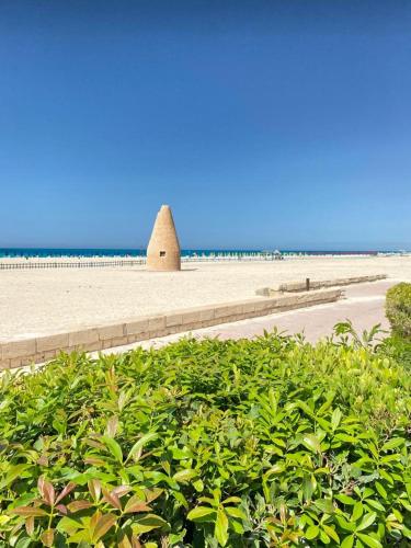 a hedge in front of a beach with a building at اول صف على البحر مارينا العلمين الساحل الشمالي 0إ in El Alamein