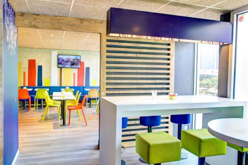 a dining room with colorful chairs and tables at ibis budget Caen Mondeville in Mondeville