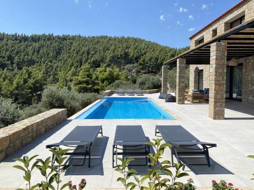 a swimming pool with chairs and a house at The Mavrolitharo Residence in Akti Salonikiou