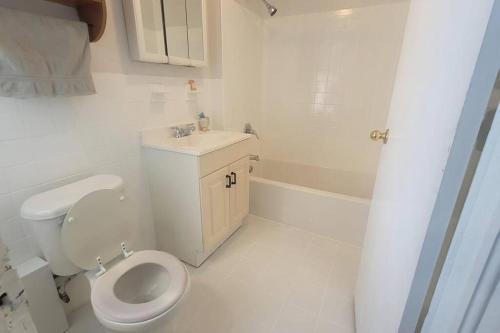 a white bathroom with a toilet and a sink at Amazing Location Train/NYC,Cafes in Montclair