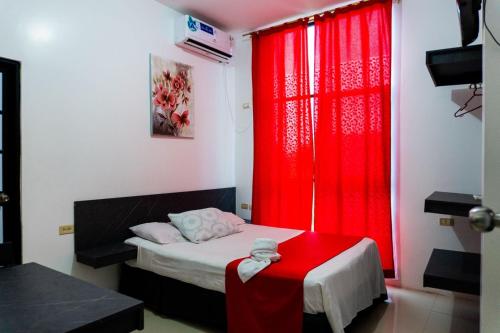 a bedroom with red curtains and a bed with a red table at HOTEL AMASH Chone in San Pablo